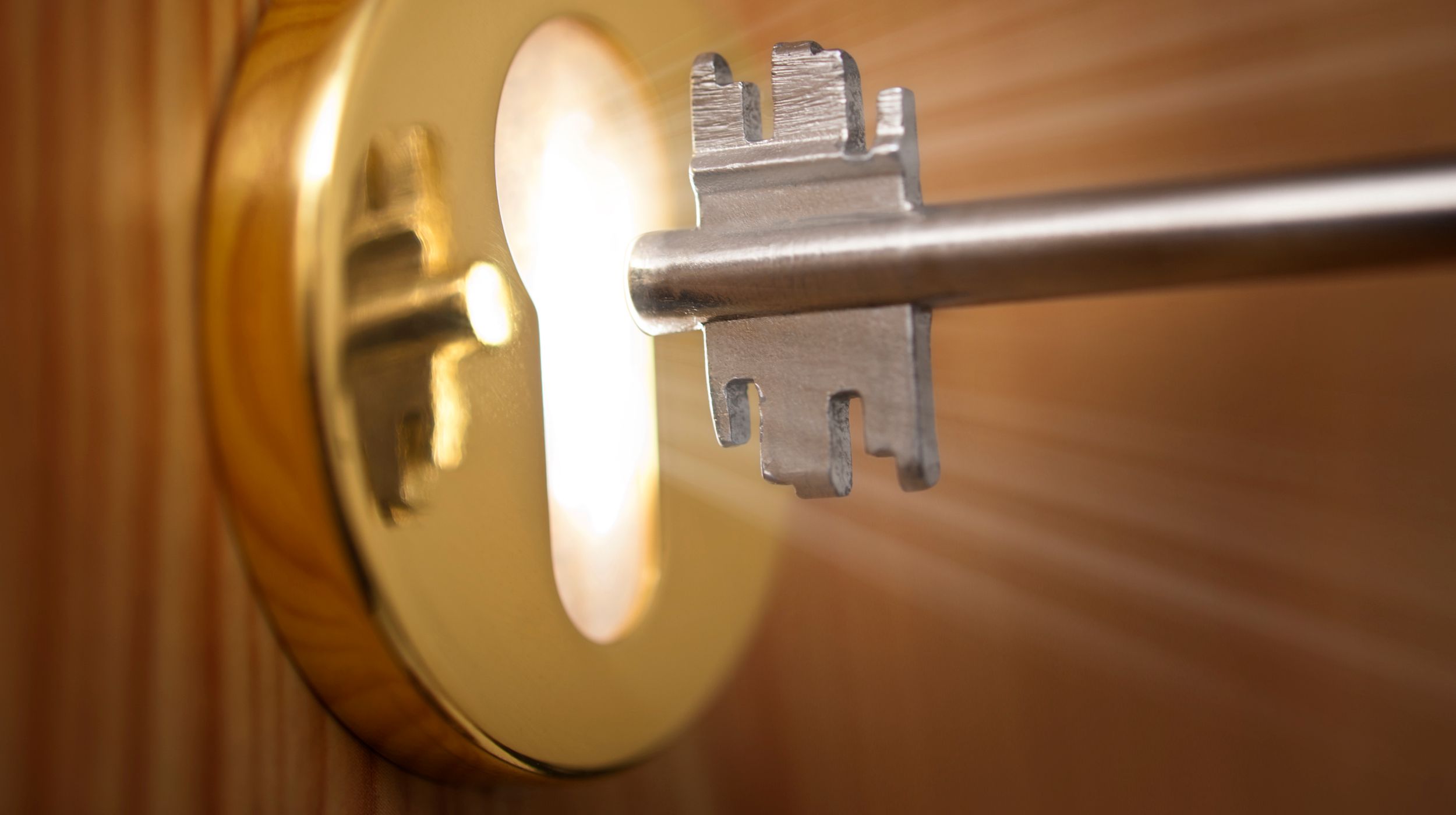 key being put in a lock with light coming out the keyhole