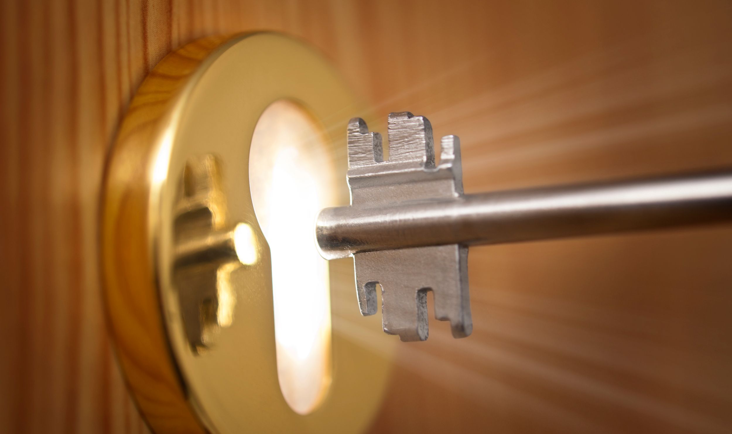key being put in a lock with light coming out the keyhole
